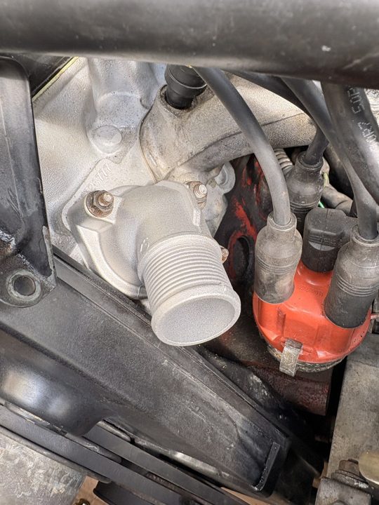 The new thermostat housing, bolted on clean.