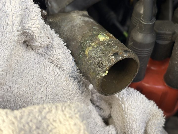 The old thermostat housing’s neck, crusted with corrosion.